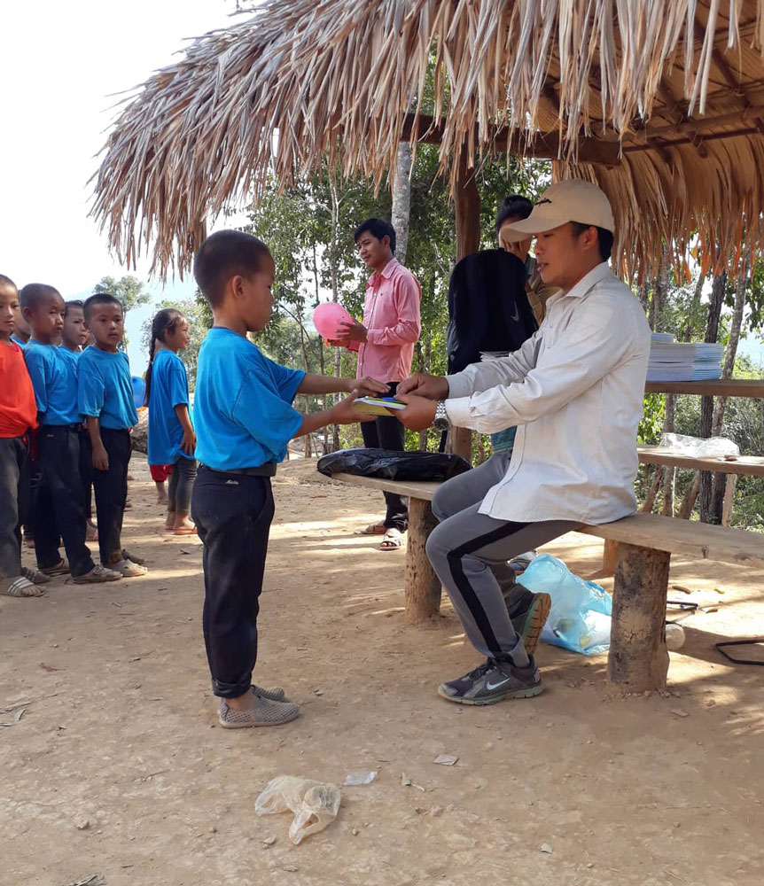 Thao verteilt Schulbücher an laotische Kinder